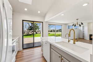 Kitchen with light wood-style flooring, baseboards, a sink, and white appliances