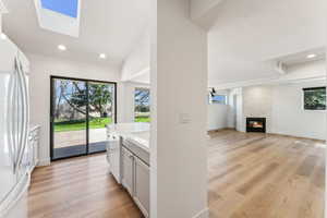Interior space featuring light countertops, a tile fireplace, light wood-style flooring, dishwashing machine, and freestanding refrigerator
