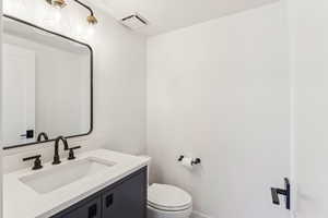 Bathroom with toilet, vanity, and visible vents