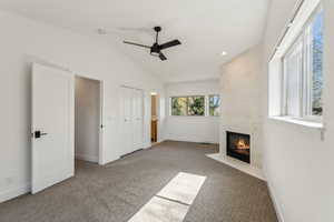 Unfurnished bedroom with vaulted ceiling, carpet, a tiled fireplace, and baseboards