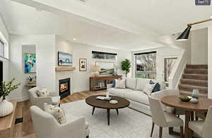 Living room featuring stairway, a glass covered fireplace, wood finished floors, and recessed lighting