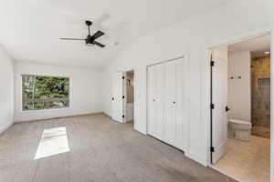 Unfurnished bedroom with baseboards, light colored carpet, lofted ceiling, a closet, and connected bathroom