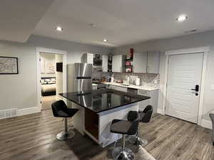 ADU Kitchen with open shelves, a sink, a breakfast bar area, appliances with stainless steel finishes, and recessed lighting