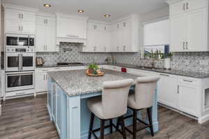 Kitchen with dark wood-style floors, white appliances, a sink, and white cabinetry