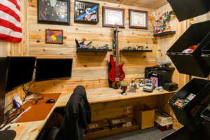 Home office featuring carpet flooring and wooden walls