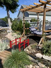 View of yard featuring a water feature, a pergola, fence