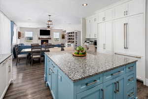 Kitchen featuring white cabinets, dark wood-style floors, a ceiling fan, a fireplace, and blue cabinetry