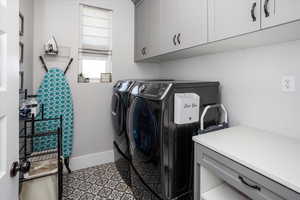 Upstairs laundry area with cabinet space, washing machine and dryer, tile patterned floors,