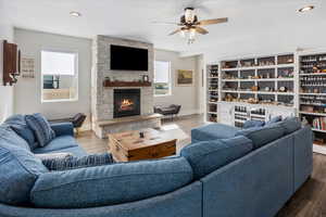 Living room with recessed lighting, a stone fireplace, wood finished floors, a ceiling fan