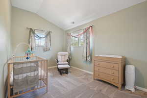 Bedroom featuring multiple windows, visible vents, a crib, and vaulted ceiling