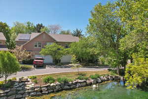 View of front of home with stone siding, stucco siding, an attached garage, driveway