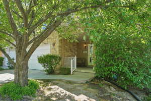 Entrance to property featuring a garage, covered porch, and stone siding