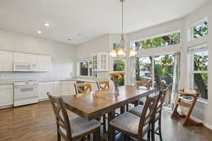 Dining area with recessed lighting, an inviting chandelier, plenty of natural light, and dark wood-type flooring