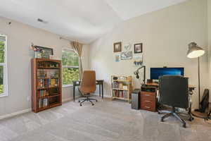 Office area with carpet floors, baseboards, lofted ceiling, and visible vents