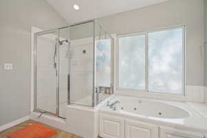 Full bathroom featuring plenty of natural light, a jetted tub, a stall shower, and finished floors