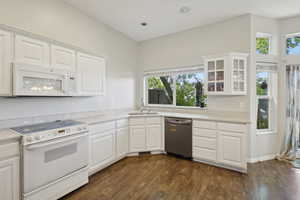 Kitchen featuring a sink, a wealth of natural light, white appliances, and glass insert cabinets