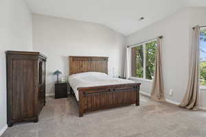 Bedroom featuring baseboards, vaulted ceiling, and light colored carpet