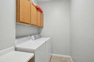 Laundry area with cabinet space, separate washer and dryer, and baseboards