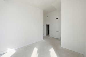 Spare room with a high ceiling and concrete flooring