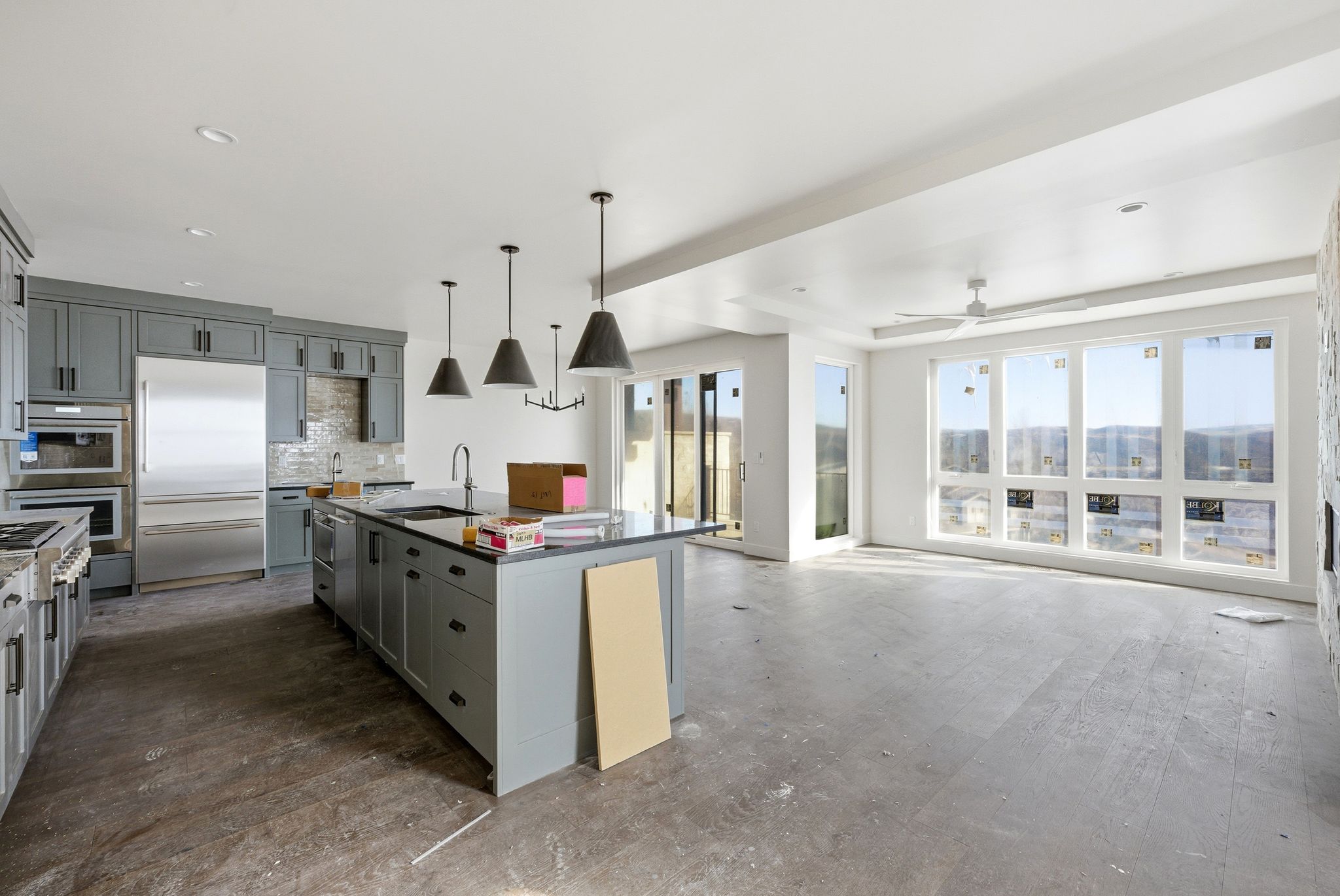 Kitchen with gray cabinets, an island with sink, stainless steel appliances, hardwood / wood-style floors, and tasteful backsplash