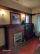 Living room featuring wallpapered walls, wood finished floors, and a fireplace