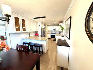 Kitchen featuring backsplash, a peninsula, glass insert cabinets, and appliances with stainless steel finishes