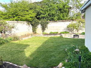 View of yard featuring a fenced backyard and a garden