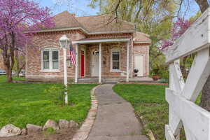 View of front of house with brick siding, a shingled roof, and a front yard