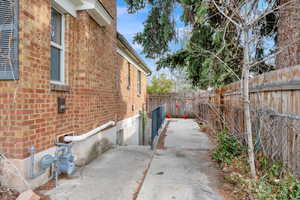 View of side of property with a fenced backyard, brick siding, and a patio