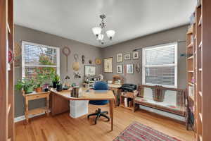 Home office featuring light wood-style flooring, a notable chandelier, and baseboards