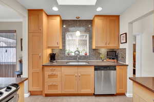 Kitchen featuring a sink, backsplash, decorative light fixtures, and dishwasher