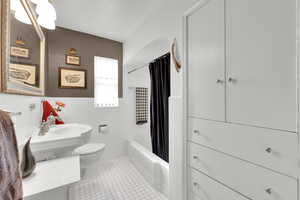 Full bathroom featuring a wainscoted wall, tile patterned floors,toilet, a sink, and tile walls