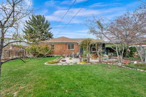 Rear view of property with brick siding, a lawn, fence, and a patio area