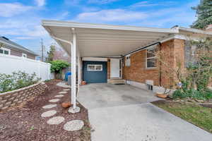 View of car parking featuring an attached carport, fence, andentry steps