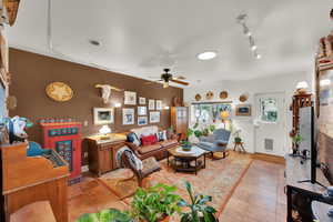 Living area featuring light tile patterned flooring, ceiling fan,baseboards, visible vents, and track lighting