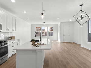 Kitchen featuring a sink, white cabinets, light countertops, backsplash, and appliances with stainless steel finishes