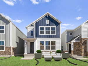 View of front of house with board and batten siding, outdoor lounge area, stone siding, and a front yard