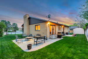 Back of property at dusk with a fenced backyard, a patio area.
