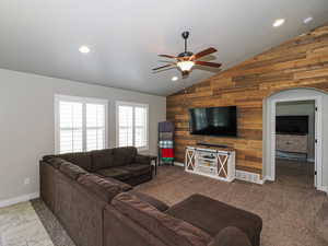 Living room with recessed lighting, lofted ceiling, wood walls, baseboards, and ceiling fan