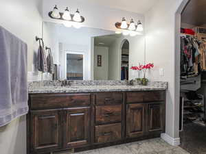 Full bath with a walk in closet, a sink, and double vanity