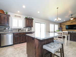 Kitchen featuring open floor plan, wooden walls, lofted ceiling, dishwasher, and a breakfast bar area