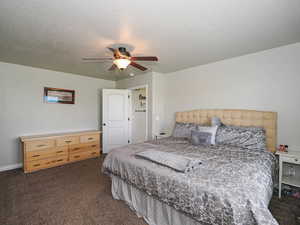 Bedroom with carpet floors, a textured ceiling, and ceiling fan