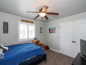 Bedroom with ceiling fan, carpet floors, baseboards, and a closet