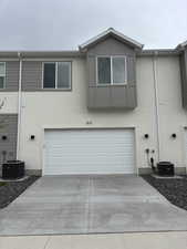 Exterior space with cooling unit, stucco siding, concrete driveway, and a garage