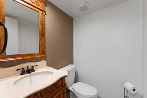 Bathroom featuring toilet, vanity, and visible vents