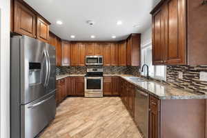 Kitchen with tasteful backsplash, stone countertops, stainless steel appliances, and a sink