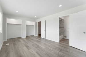 Unfurnished bedroom featuring light wood-style flooring, visible vents, recessed lighting, and two closets