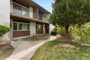 Exterior space featuring brick siding, a balcony, and fence