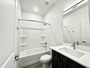 Full bathroom featuring wood finished floors, vanity, tub / shower combination, toilet, and visible vents