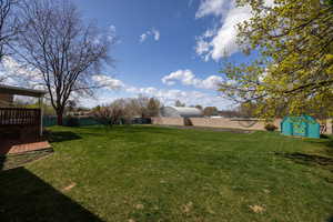View of yard featuring a fenced backyard, a wooden deck, an outbuilding, and a shed